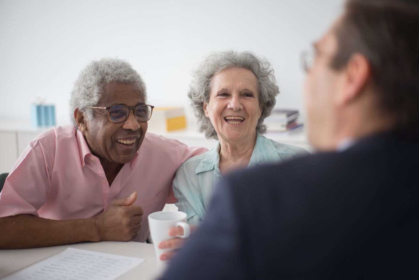 Two senior women laughing together over coffee