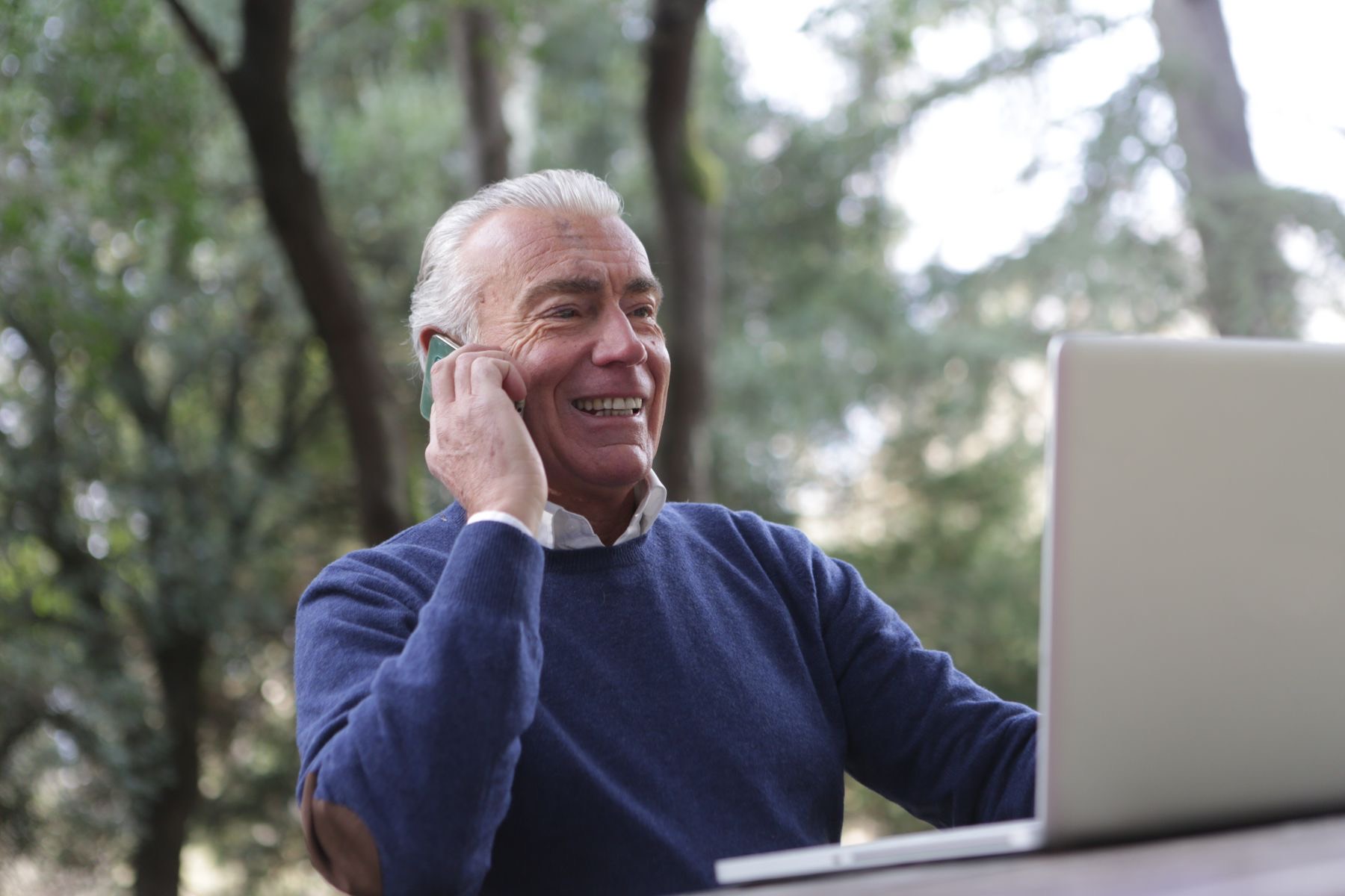 A smiling senior man talking on the phone outdoors