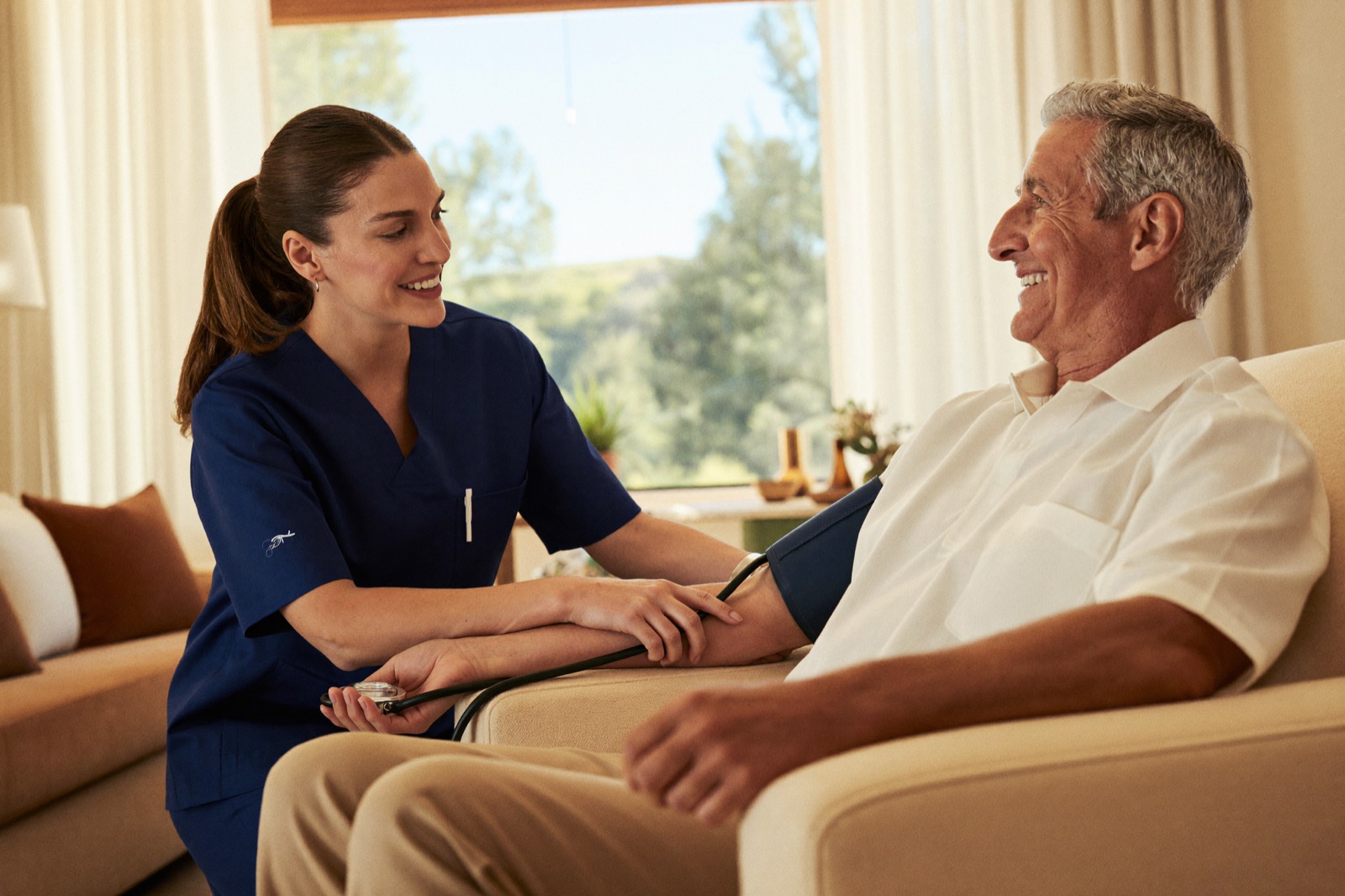 A TruLife nurse checking a senior man's blood pressure in his sunlit living room